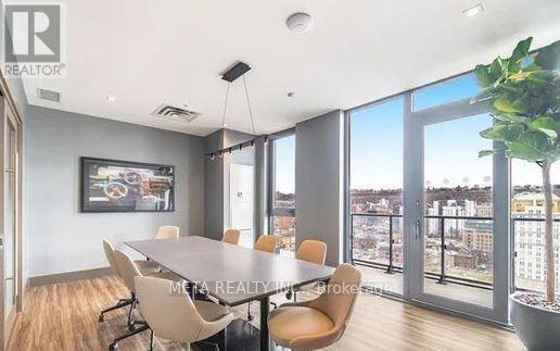A conference room with a long table and chairs, a framed picture on the wall, and a view of the city through the windows.