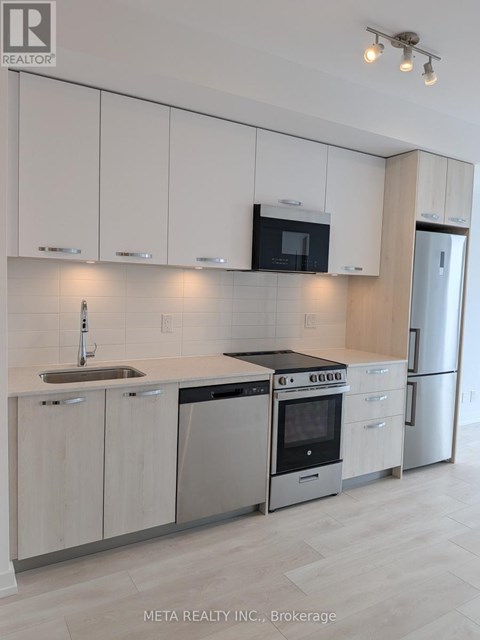 A modern kitchen with white cabinets and stainless steel appliances.