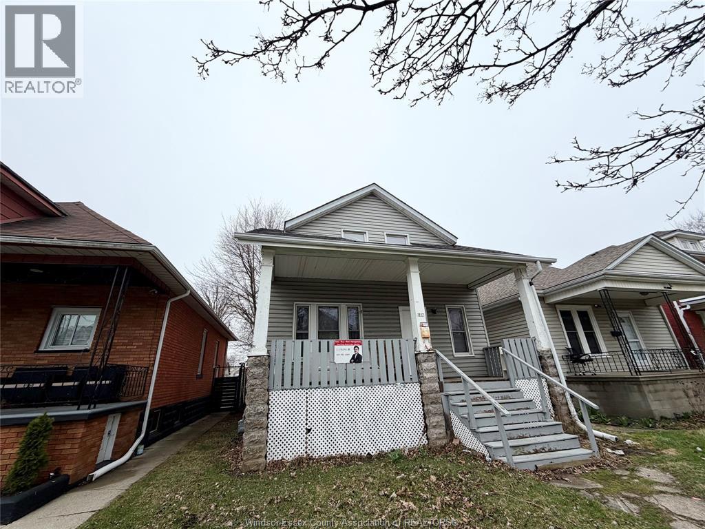 A house with a grey front porch and a red door.