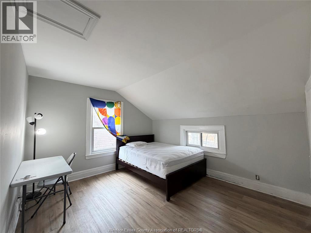 A bedroom with a bed, table, and two windows.