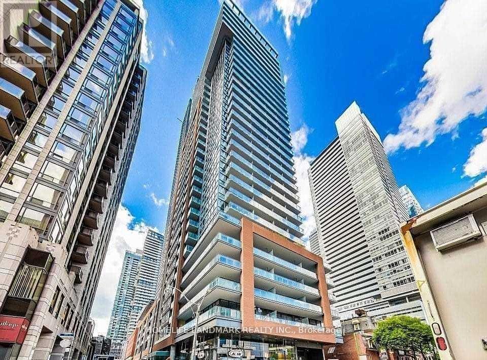 A tall building with a glass facade stands in front of a row of shorter buildings.