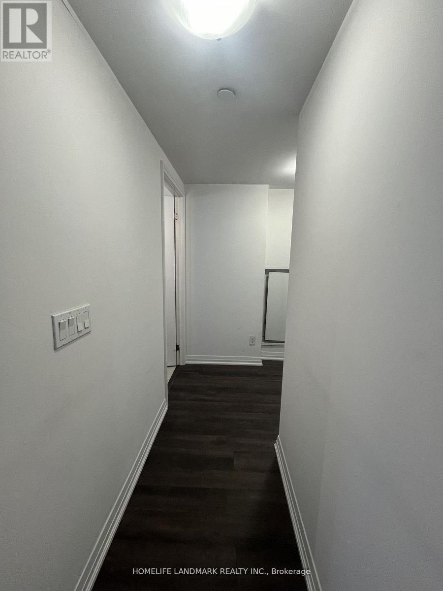 A long hallway with a light on the ceiling and a door at the end.
