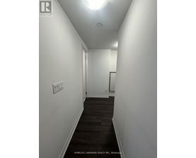 A long hallway with a light on the ceiling and a door at the end.