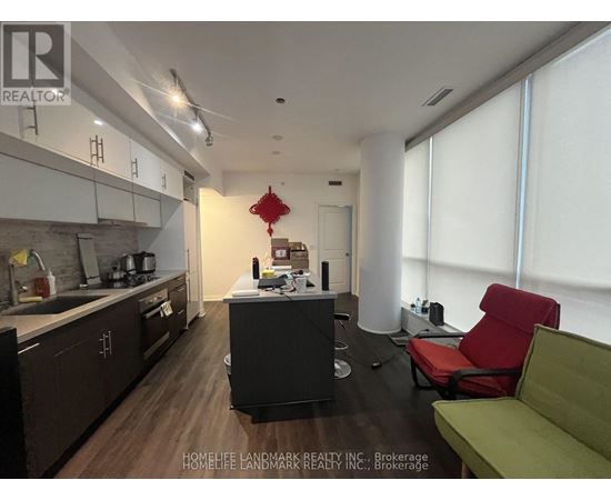 A modern kitchen with dark wood floors and a green sofa.