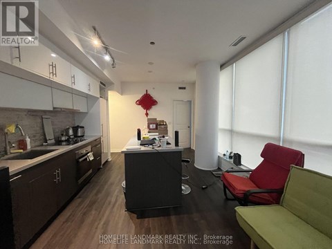 A modern kitchen with dark wood floors and a green sofa.