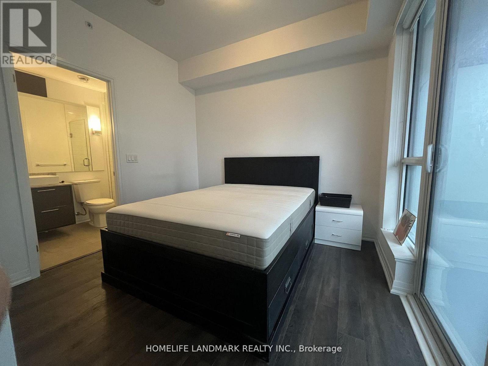 A bedroom with a large bed, a nightstand, and a small table.
