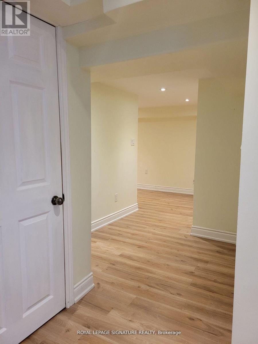 A white door is on the left of a hallway with wooden floors.