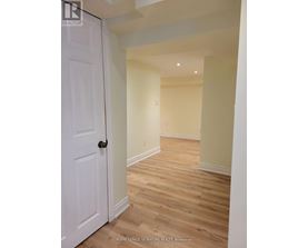 A white door is on the left of a hallway with wooden floors.