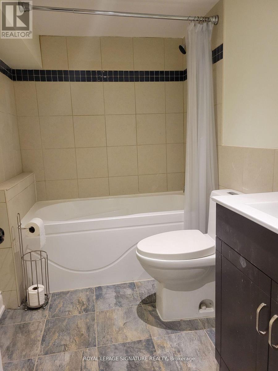 A white toilet sits next to a bathtub in a bathroom.