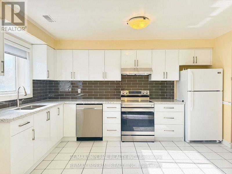 A kitchen with white cabinets and a black backsplash.
