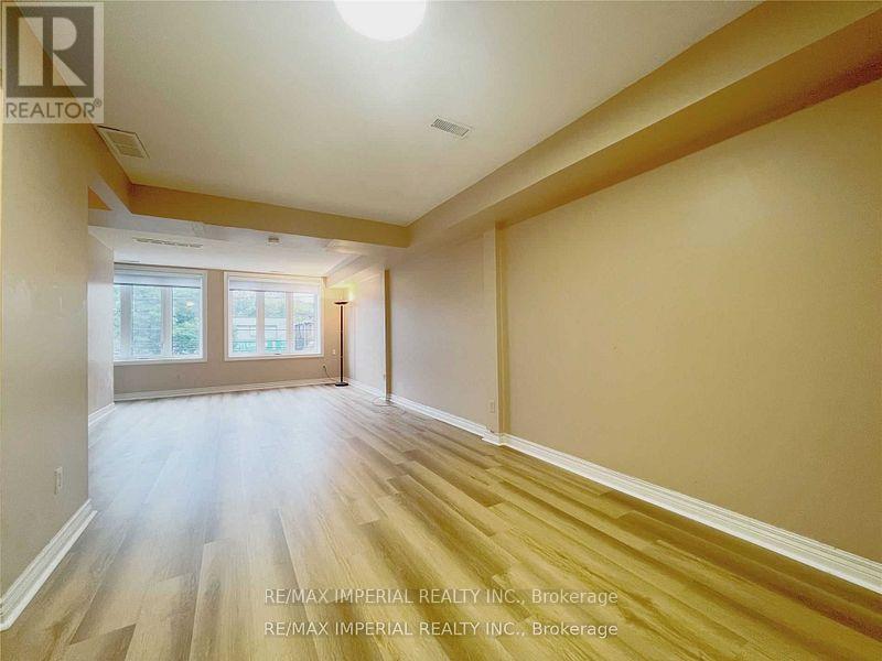 A spacious room with wooden flooring and a large window.