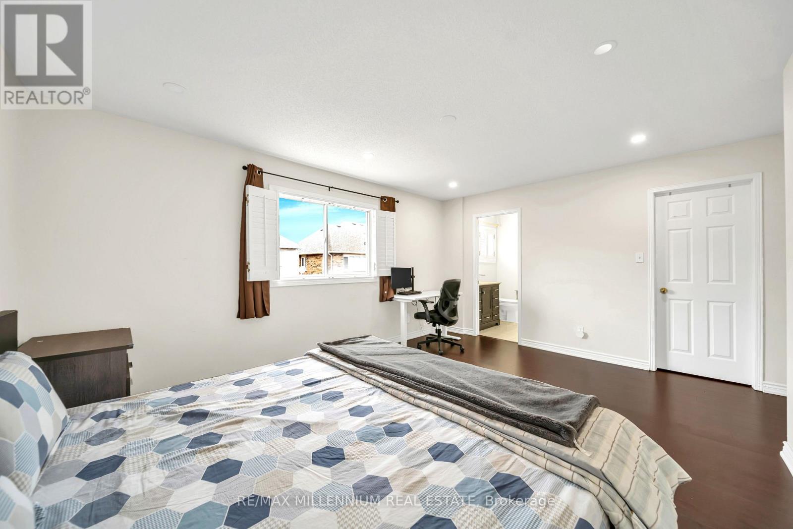 A bedroom with a large bed and a window overlooking a house.