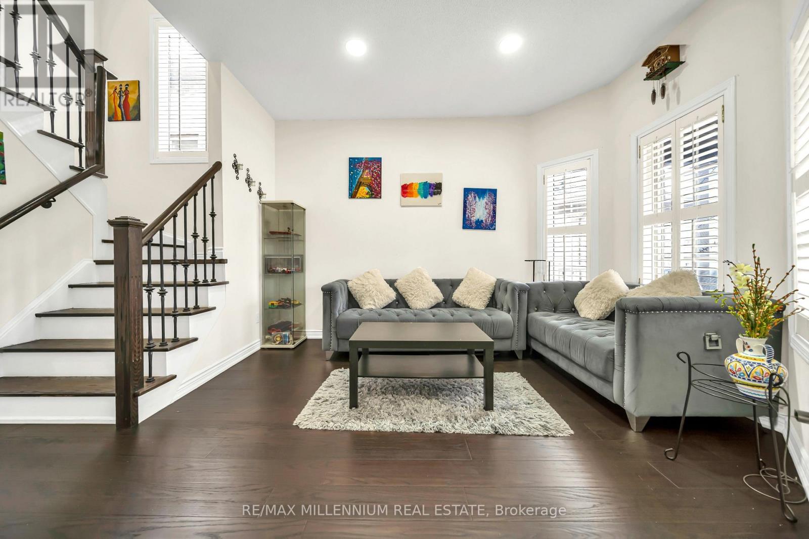 A living room with a grey couch and a staircase.