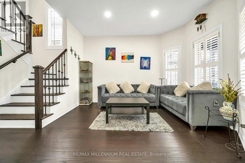 A living room with a grey couch and a staircase.