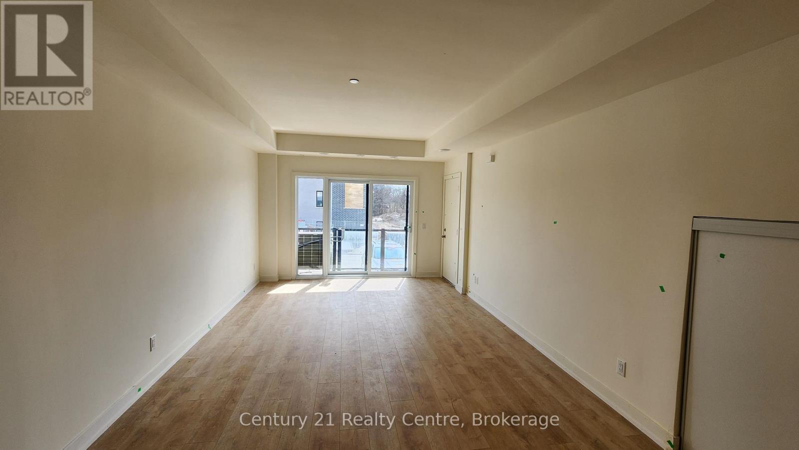 A spacious room with wooden flooring and a doorway leading to another room.