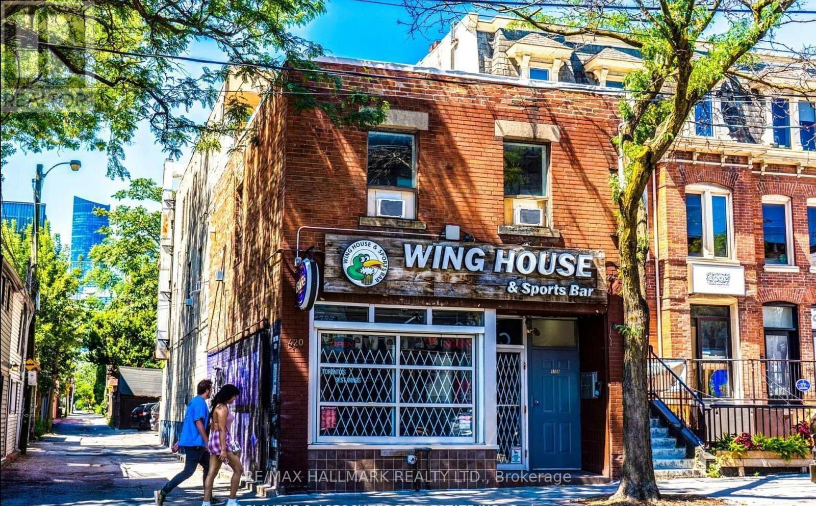 A couple walking past a building with a sign that says "Wing House".