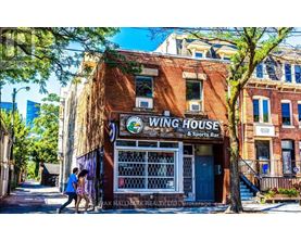 A couple walking past a building with a sign that says "Wing House".