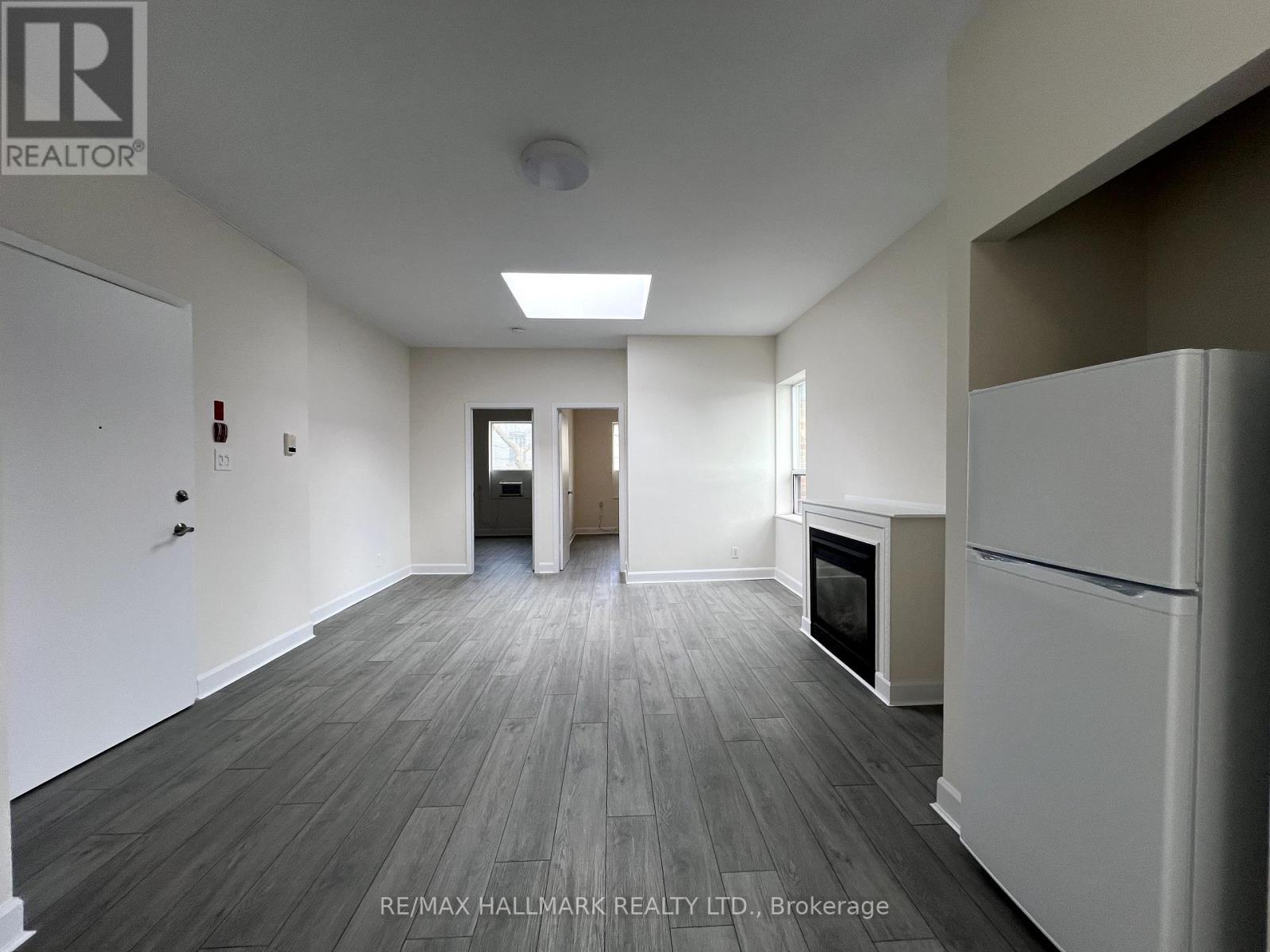 A spacious room with a fireplace and a refrigerator.