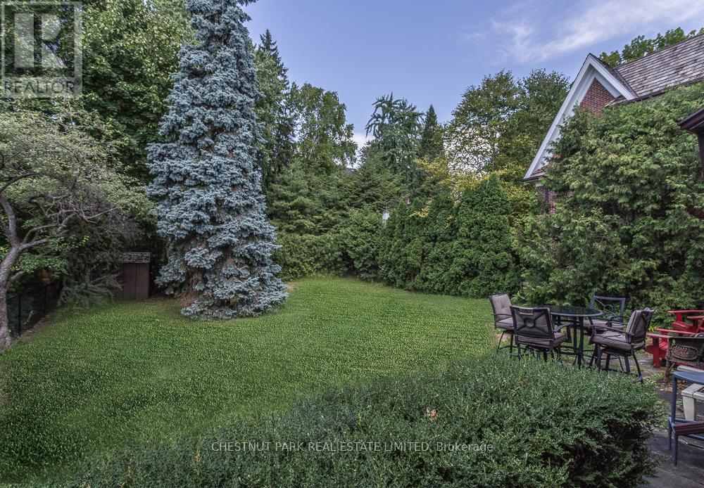 A backyard with a lawn, trees, and a table set for four.