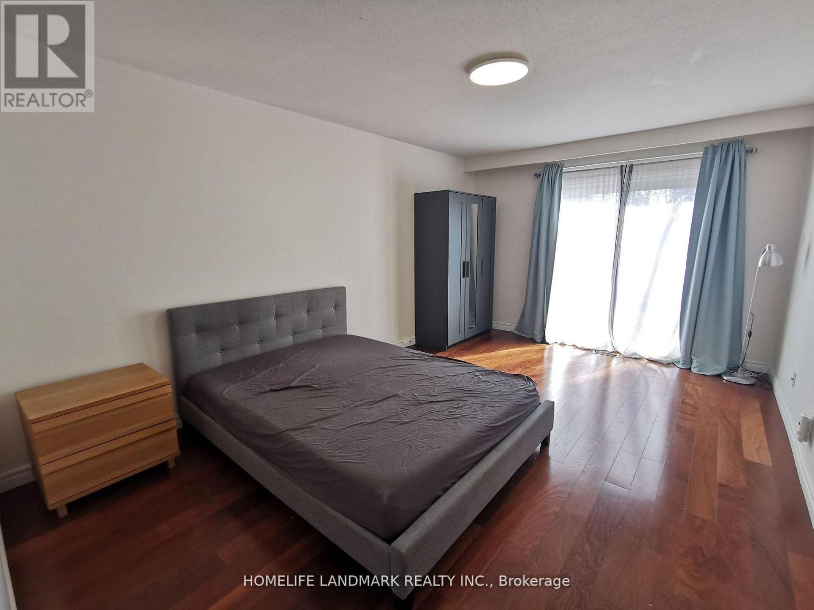 A bedroom with a bed, nightstand, and wardrobe.