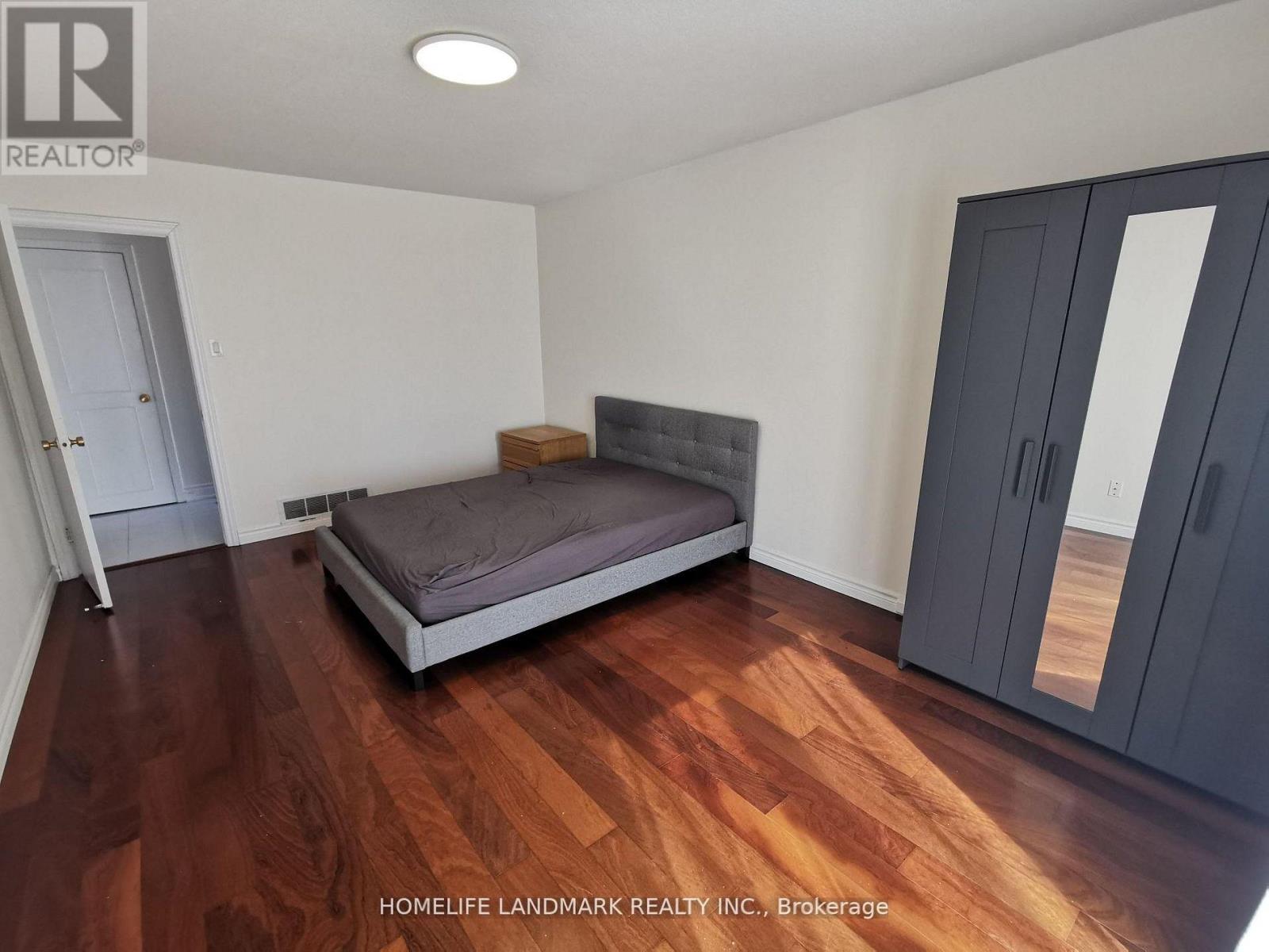 A bedroom with a bed, wardrobe and a wooden floor.
