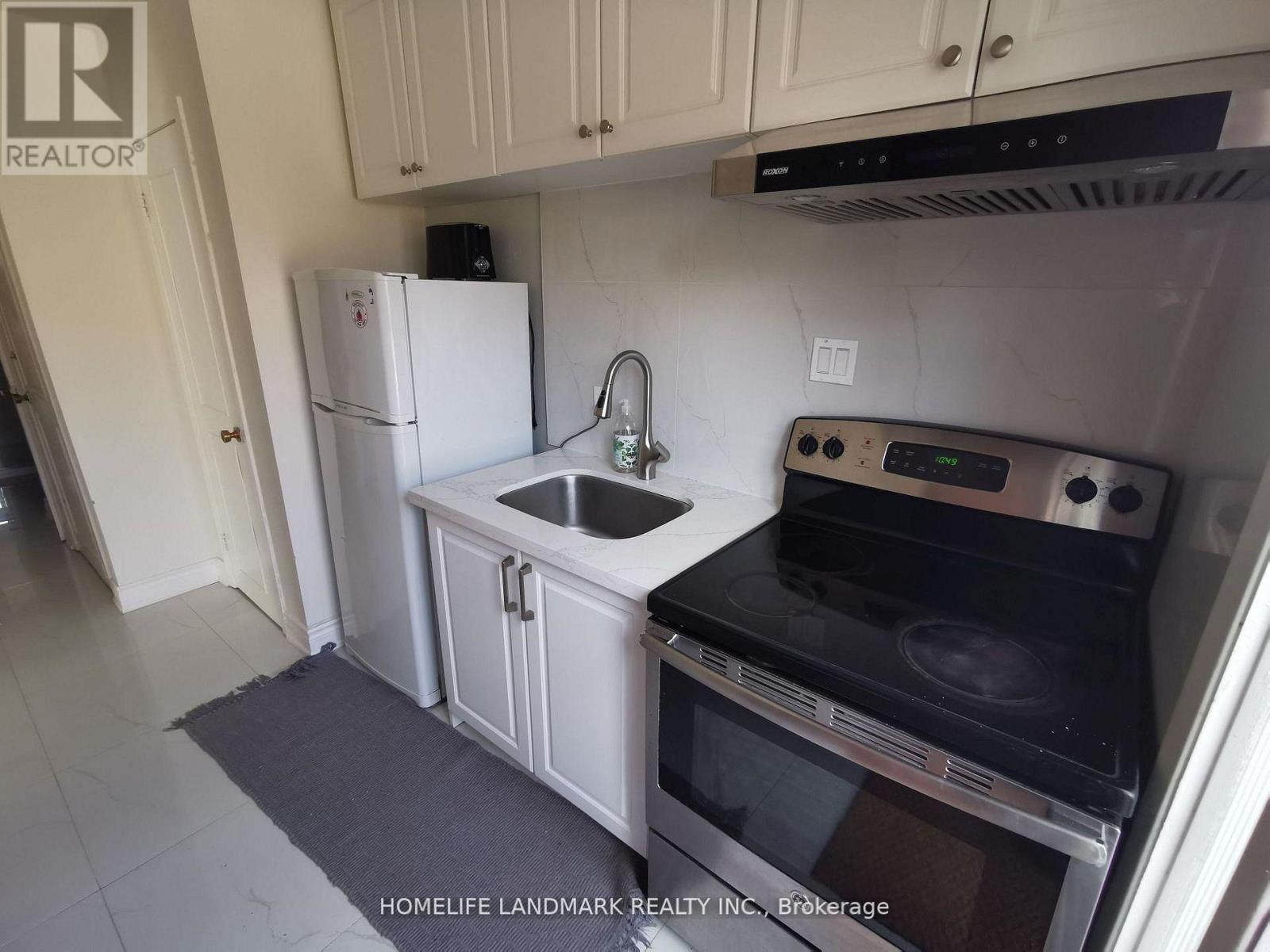 A kitchen with a white fridge, black stove, and white cabinets.