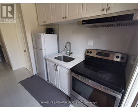 A kitchen with a white fridge, black stove, and white cabinets.