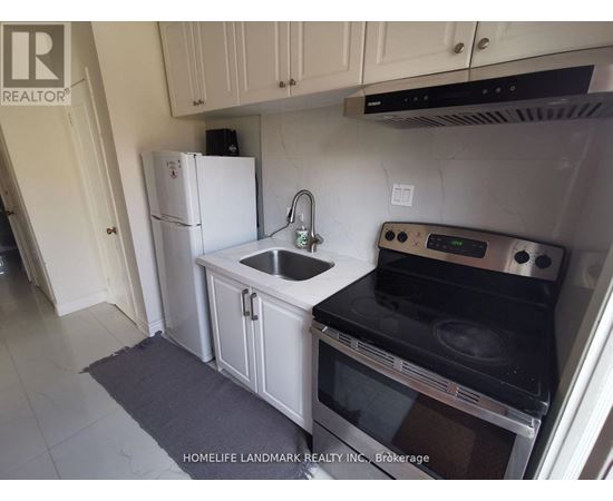 A kitchen with a white fridge, black stove, and white cabinets.