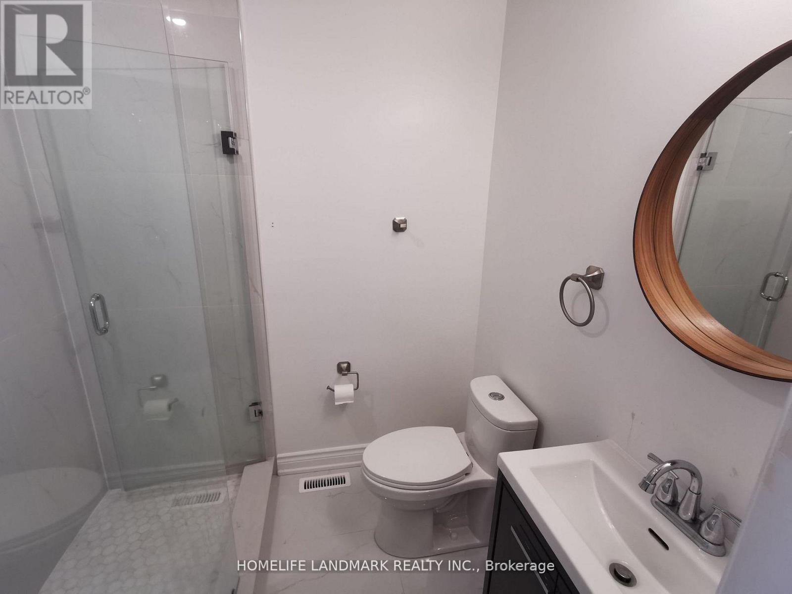 A white toilet in a small bathroom with a glass shower door.