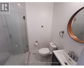 A white toilet in a small bathroom with a glass shower door.