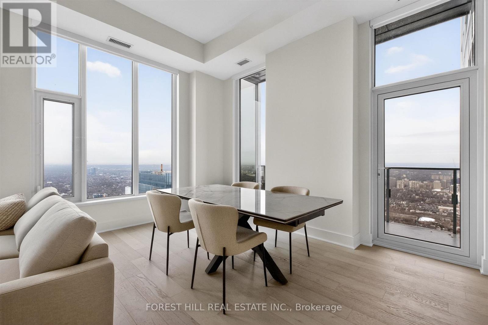A real estate listing image of a modern dining room with a view of the city.