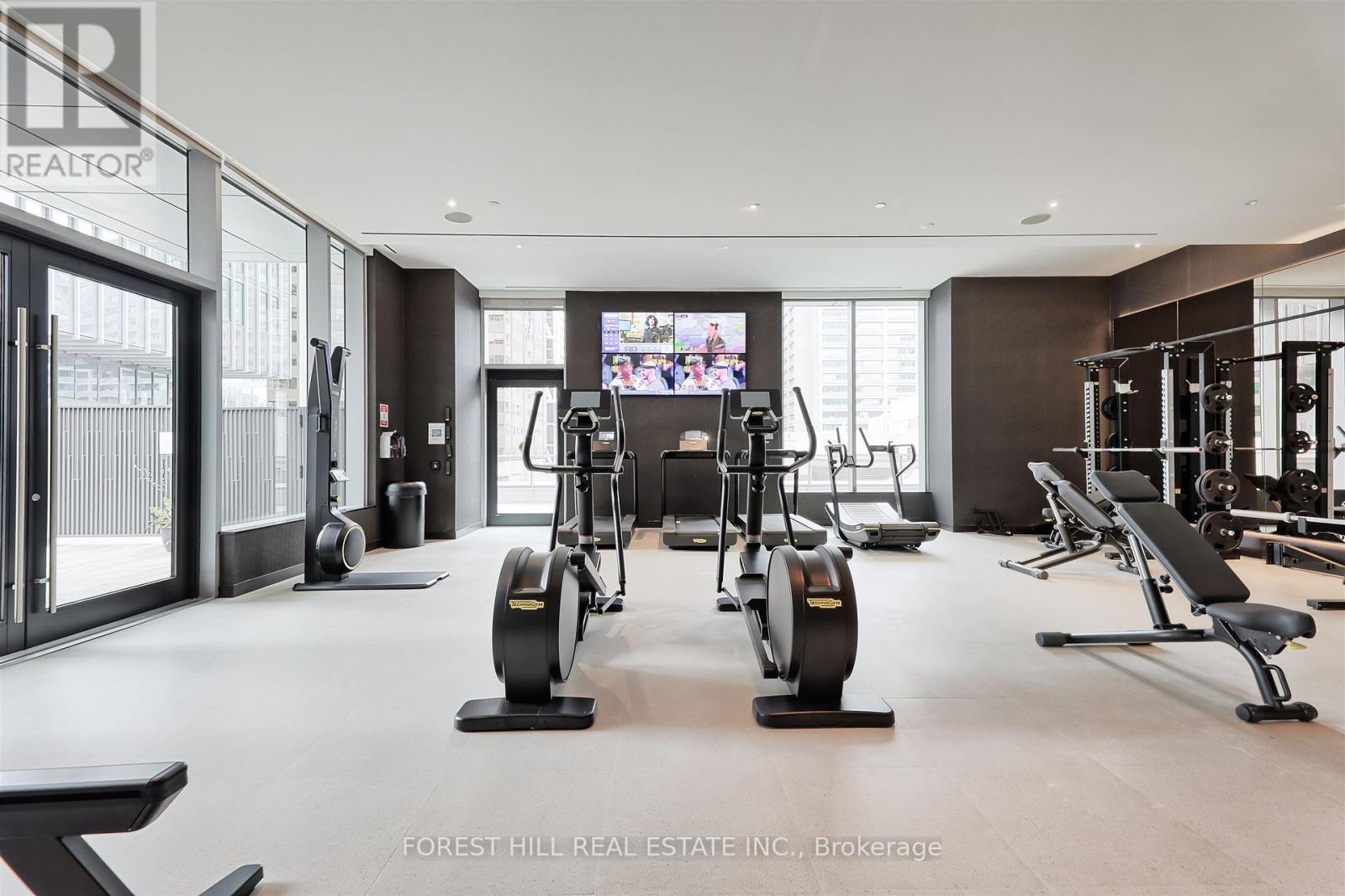 A gym with a row of exercise bikes and a television mounted on the wall.