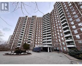 A tall apartment building with a parking lot in front.