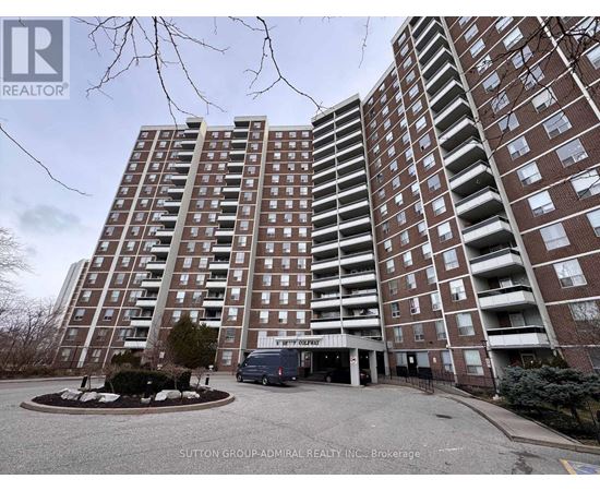 A tall apartment building with a parking lot in front.