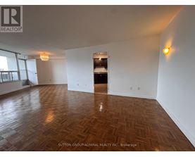 A room with wooden flooring and white walls, with a logo of REALTOR in the top left corner.