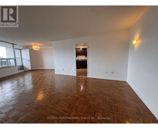 A room with wooden flooring and white walls, with a logo of REALTOR in the top left corner.