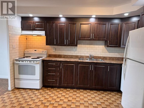 A kitchen with brown cabinets and a white stove.