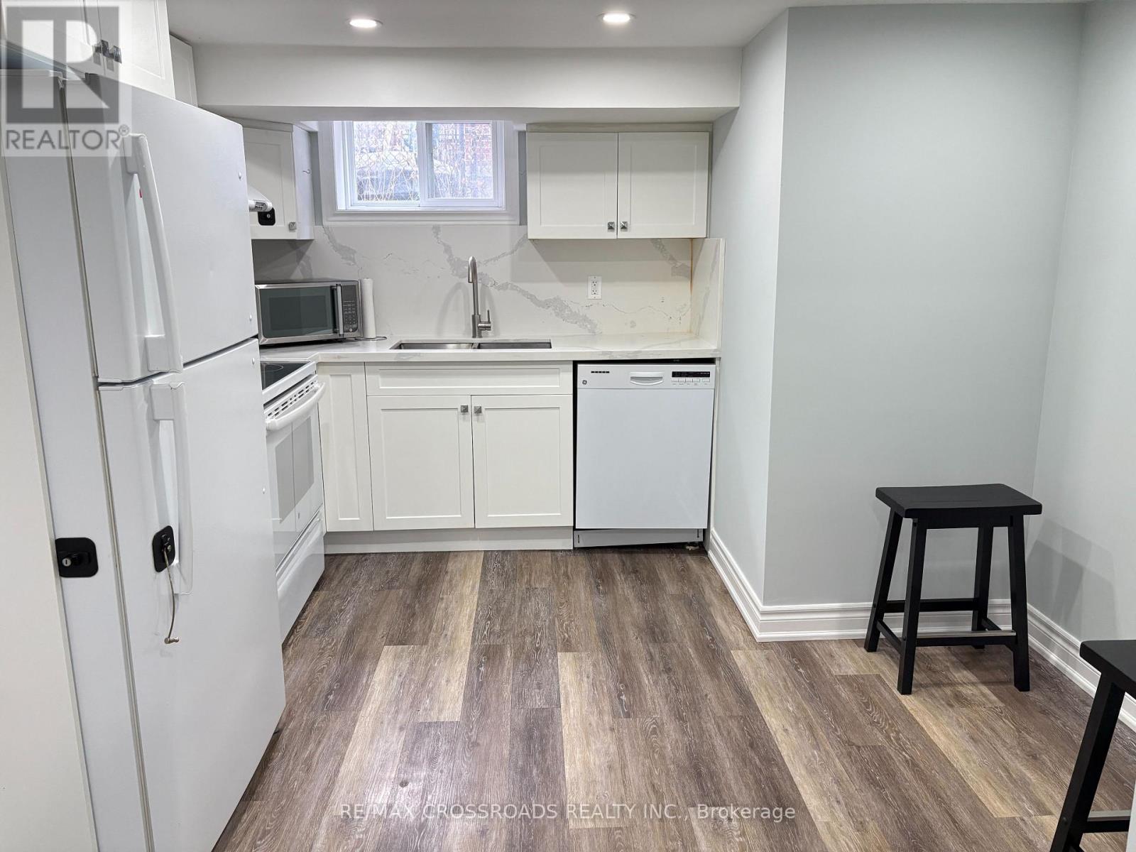 A kitchen with white appliances and a wooden floor.