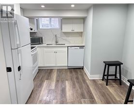 A kitchen with white appliances and a wooden floor.