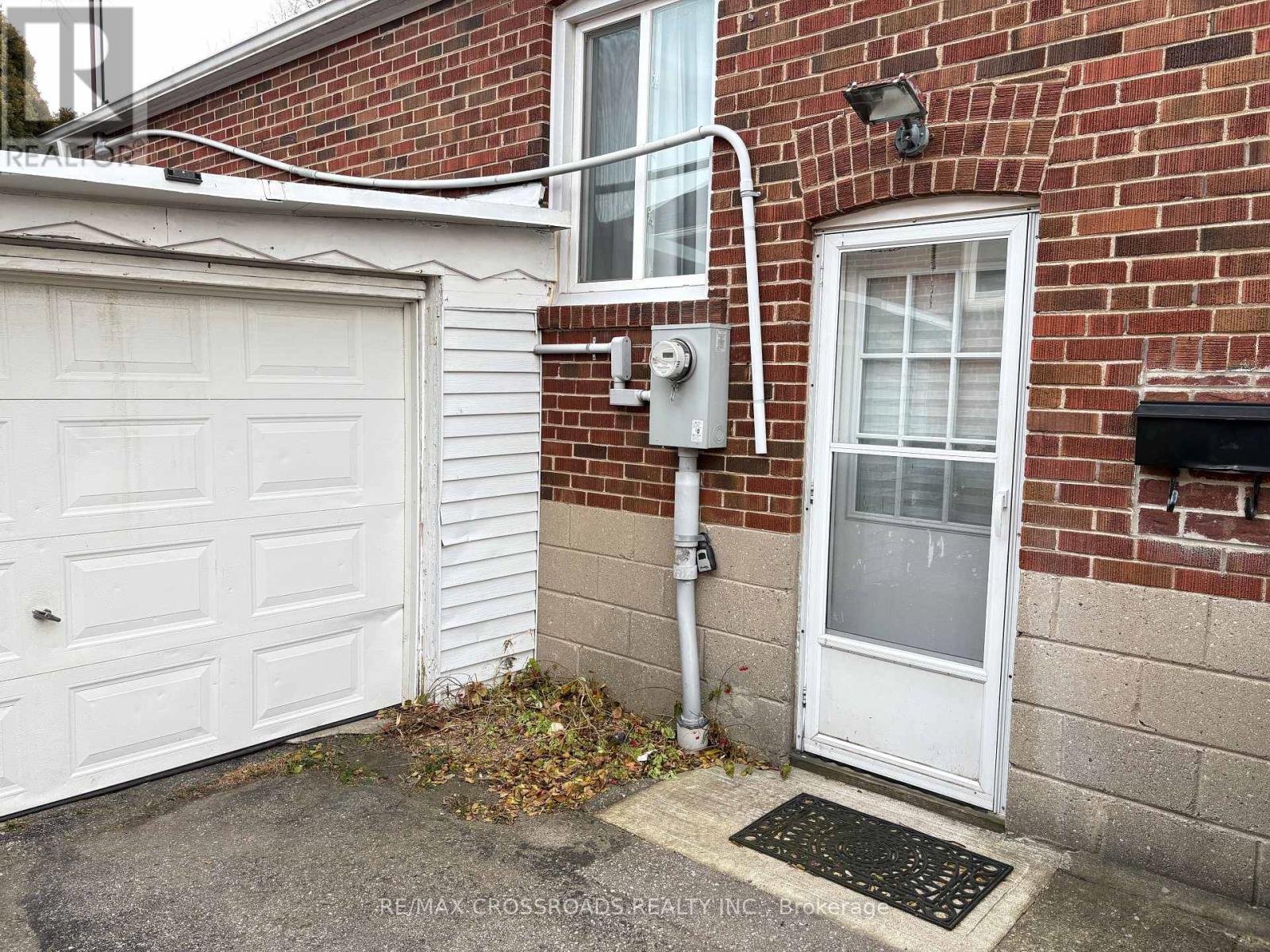 A white garage door is on the left of a brick building.