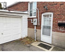 A white garage door is on the left of a brick building.