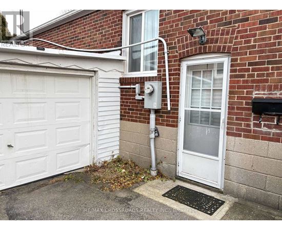 A white garage door is on the left of a brick building.