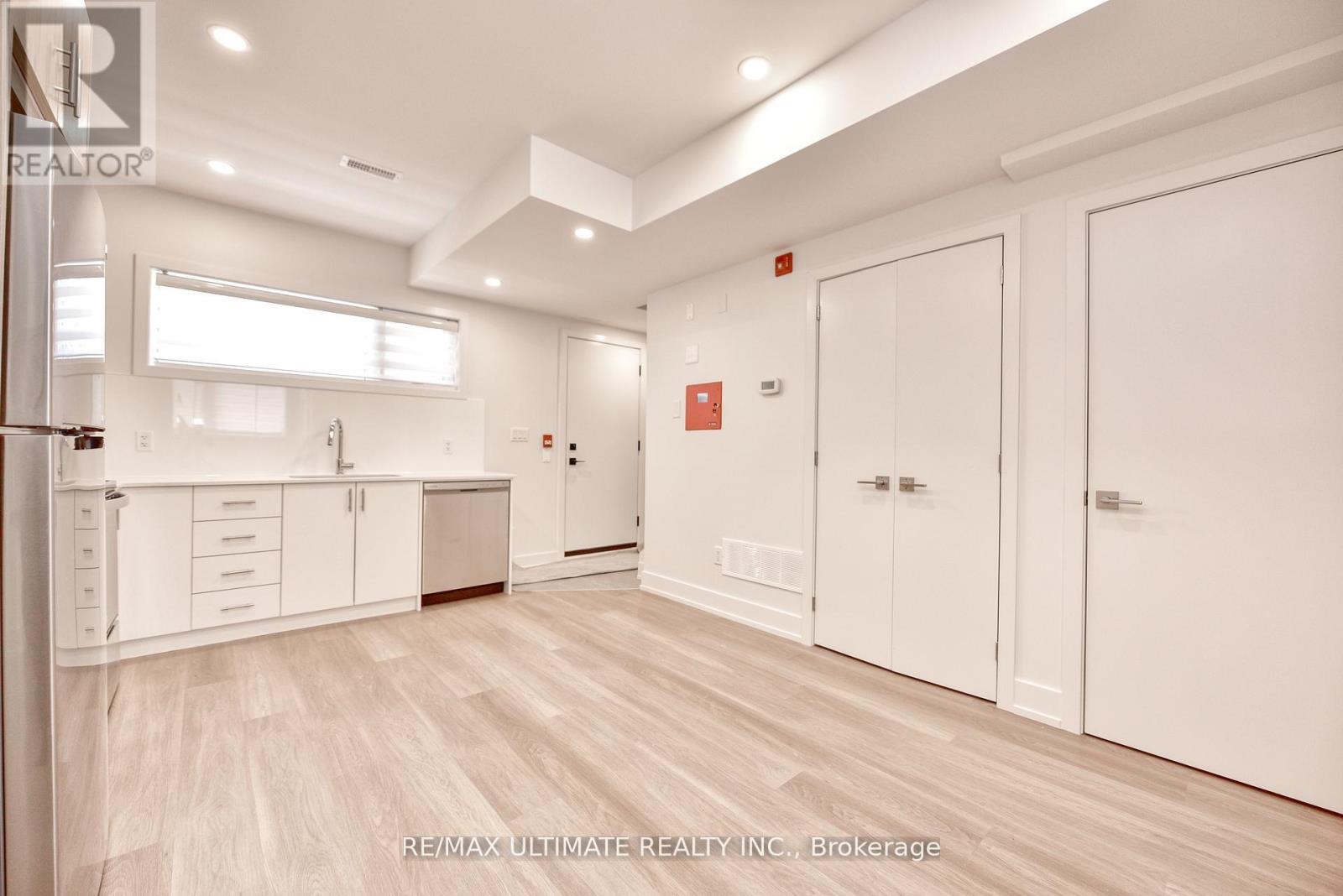 A spacious kitchen with white cabinets and a wooden floor.