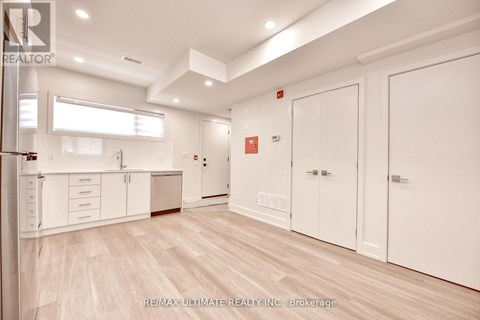 A spacious kitchen with white cabinets and a wooden floor.