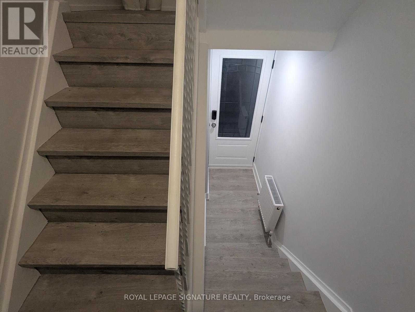 A staircase with a white railing and wooden steps leading to a door.