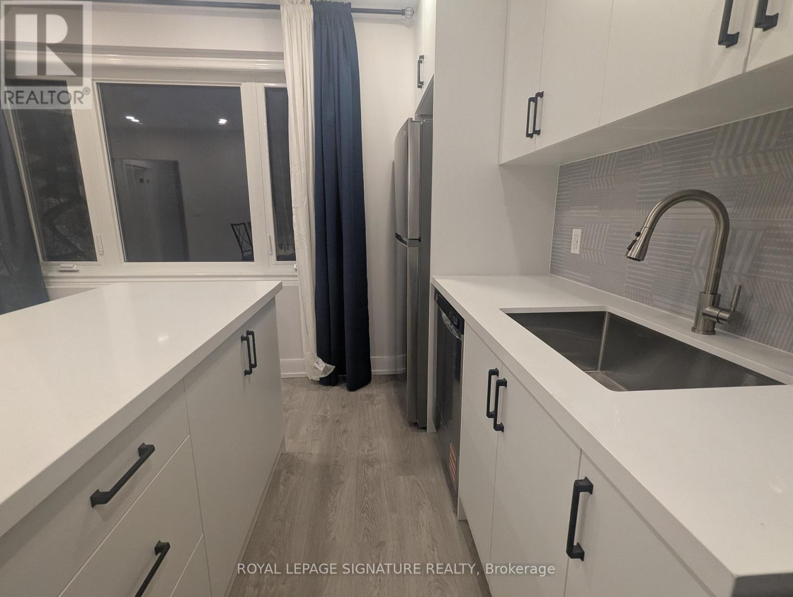 A modern kitchen with white cabinets and a stainless steel sink.