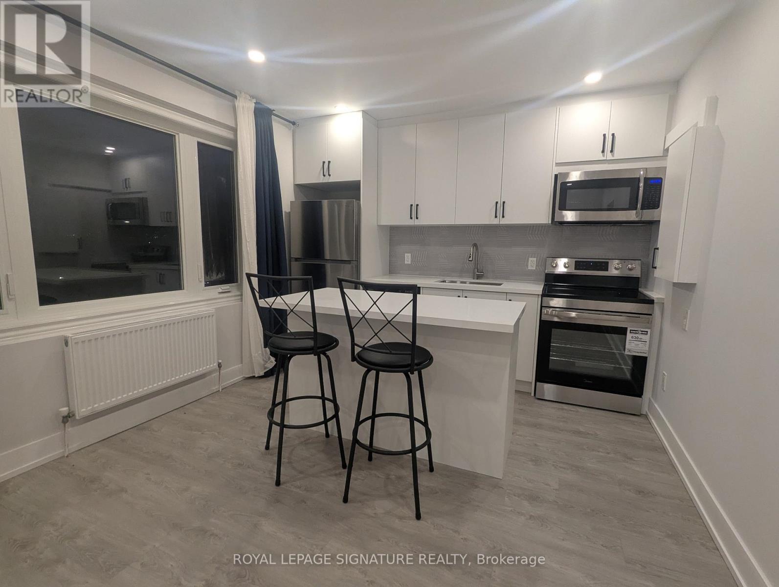 A kitchen with white cabinets and a grey floor.