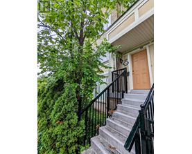 A brown door is on the right side of a staircase with a black railing.