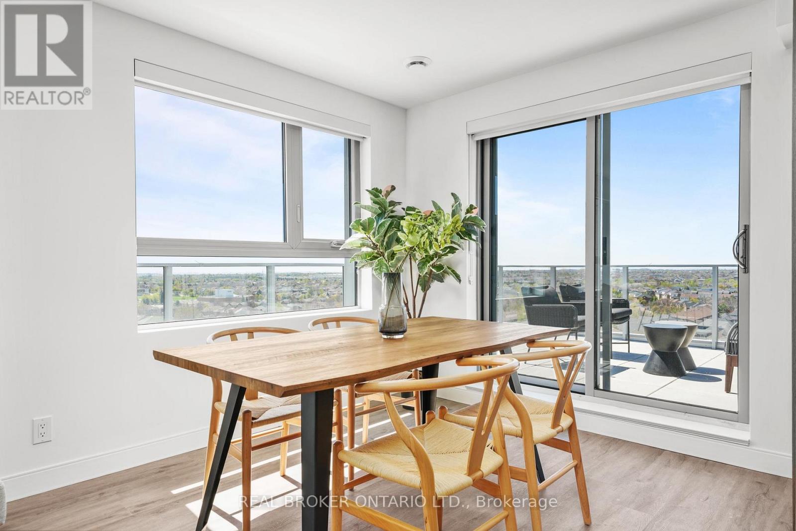 A dining room with a wooden table and chairs with a view of the city.