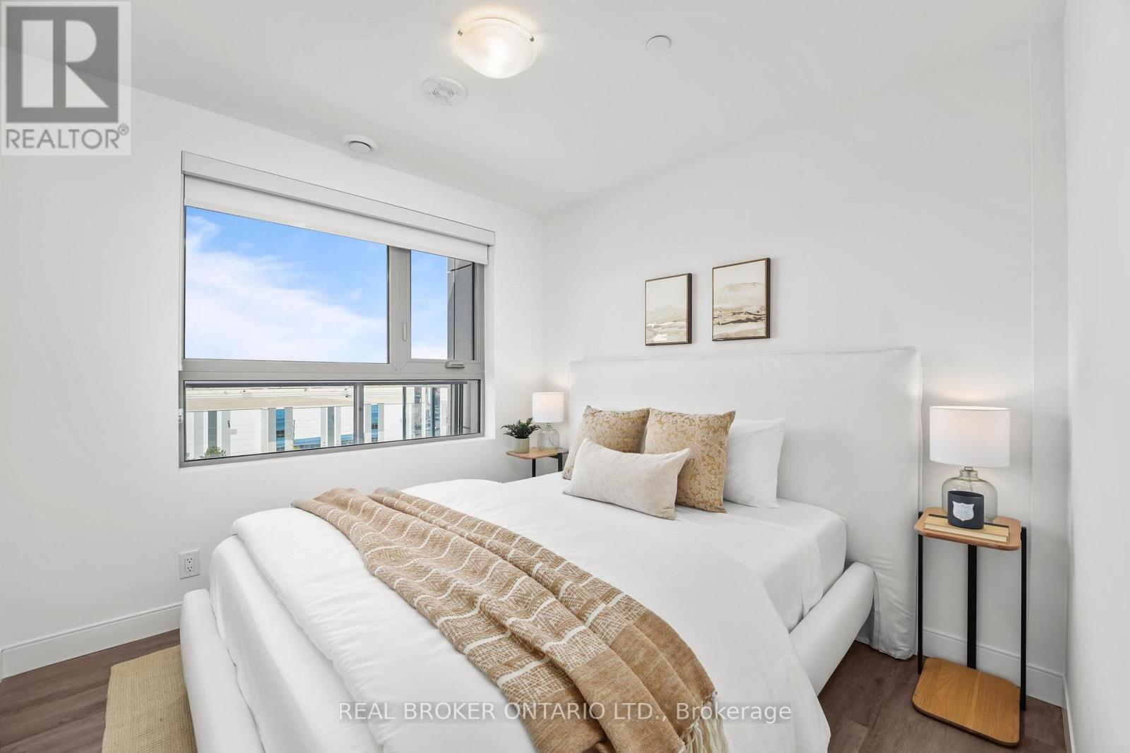A bedroom with a large bed and a window overlooking a cityscape.